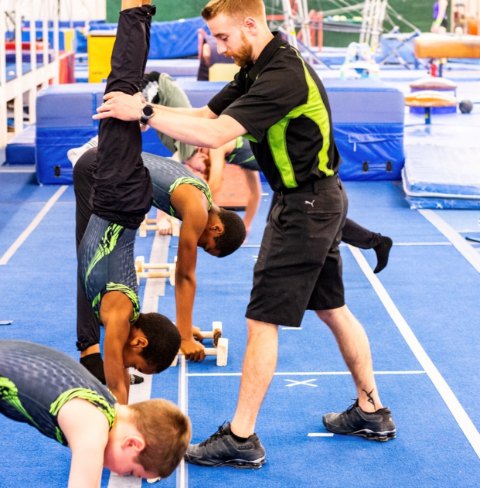 CNY Gym Centre coaches spotting young gymnasts practicing handstands